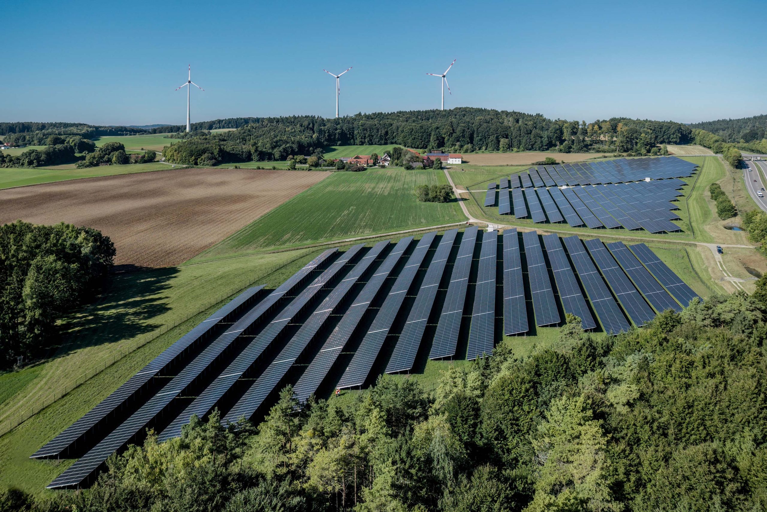 Drohnenaufnahme des Perigus-Solarparks Hatzenhof mit dem Windpark Granswang im Hintergrund
