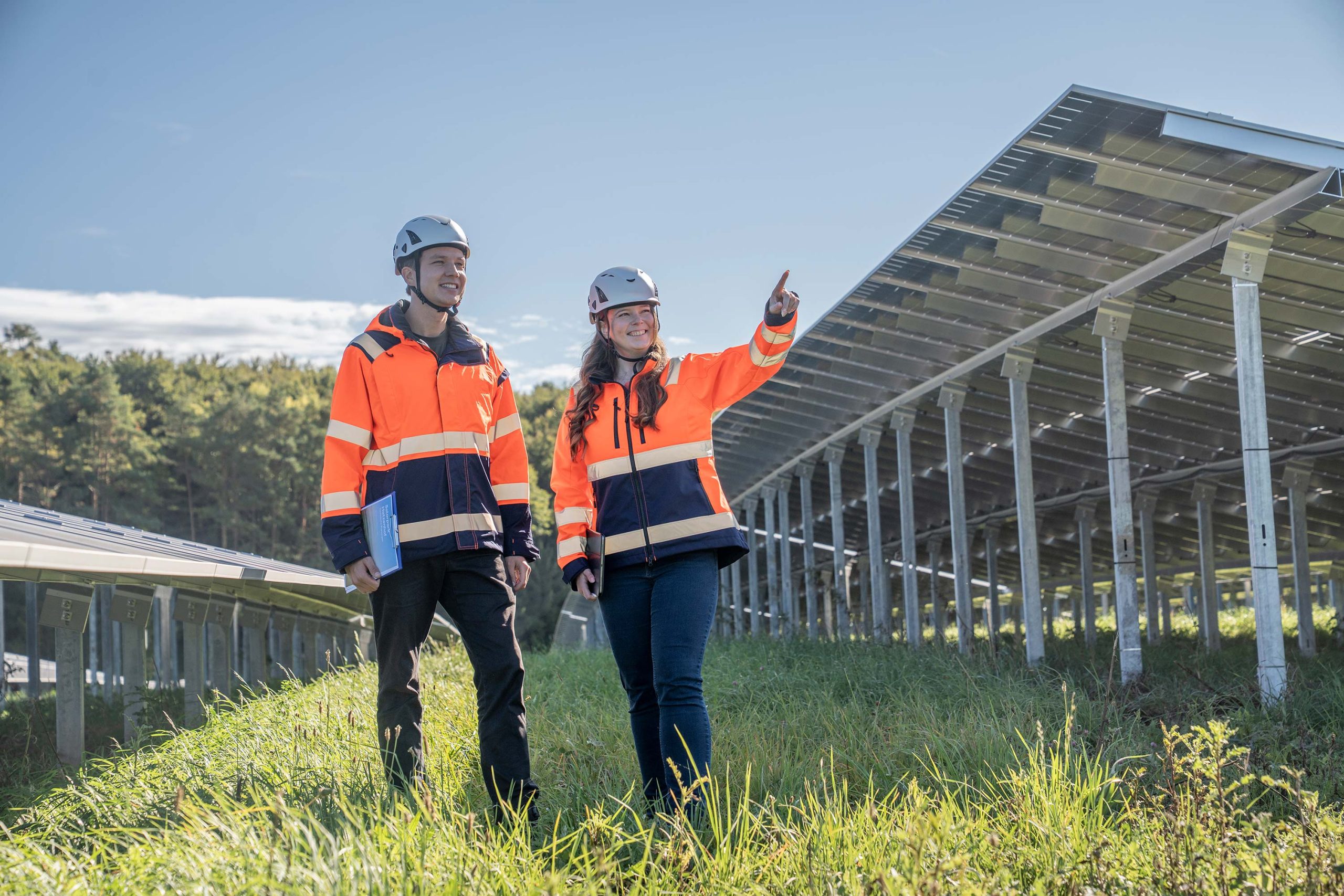 Zwei Mitarbeitende von Perigus Energy stehen im Solarpark Hatzenhof