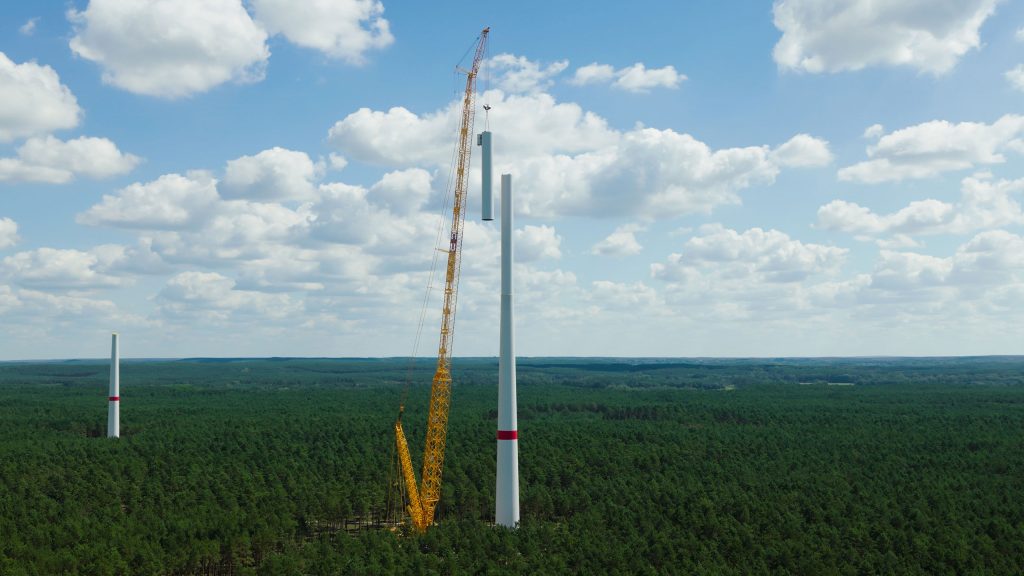 Ein Kran hebt ein Stahlturm-Segment einer Windenergieanlage im Perigus-Windpark Bahren West in die Höhe